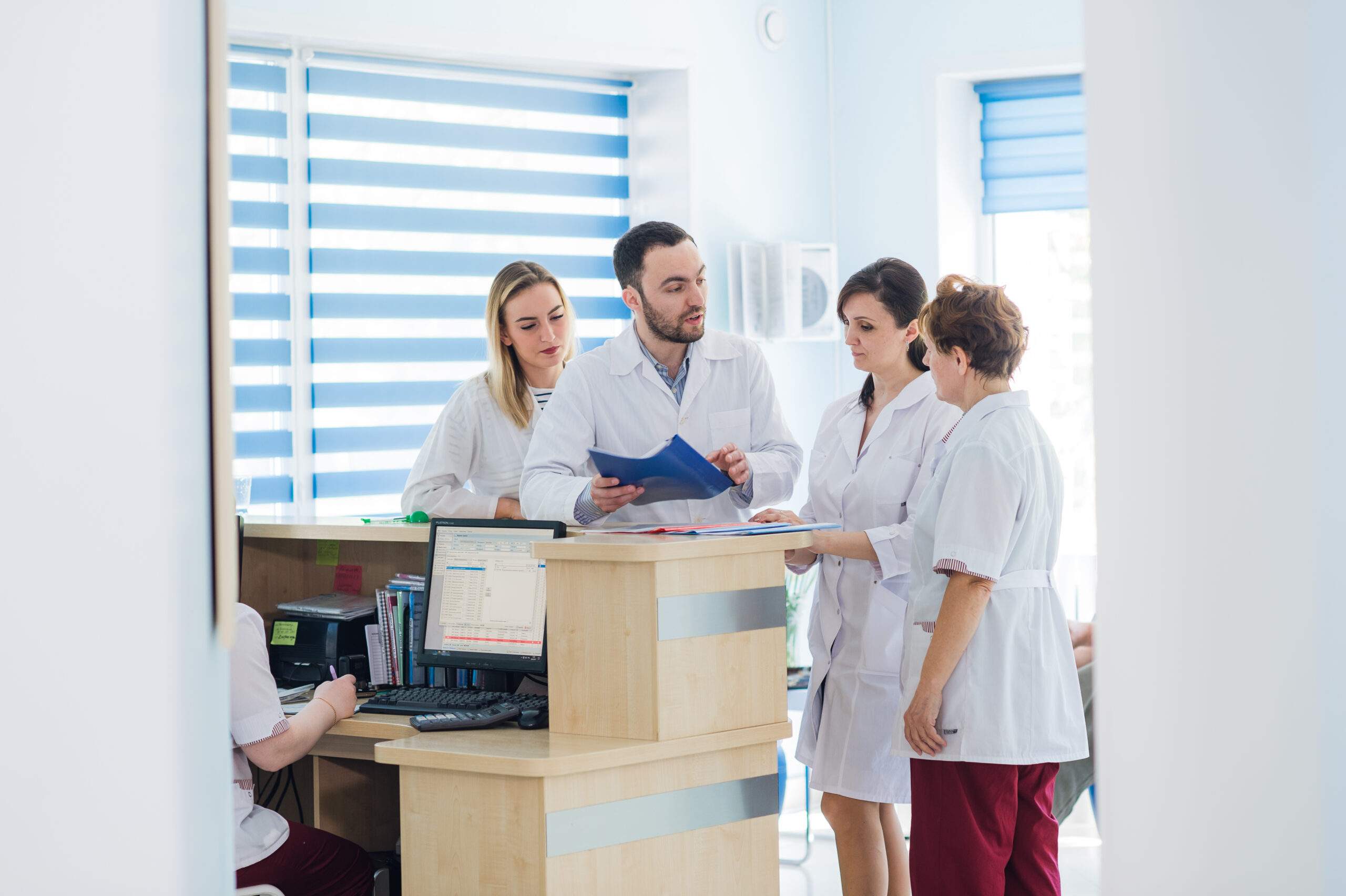 Healthcare professionals discussing patient records at a reception desk in a Massage Therapy Centre