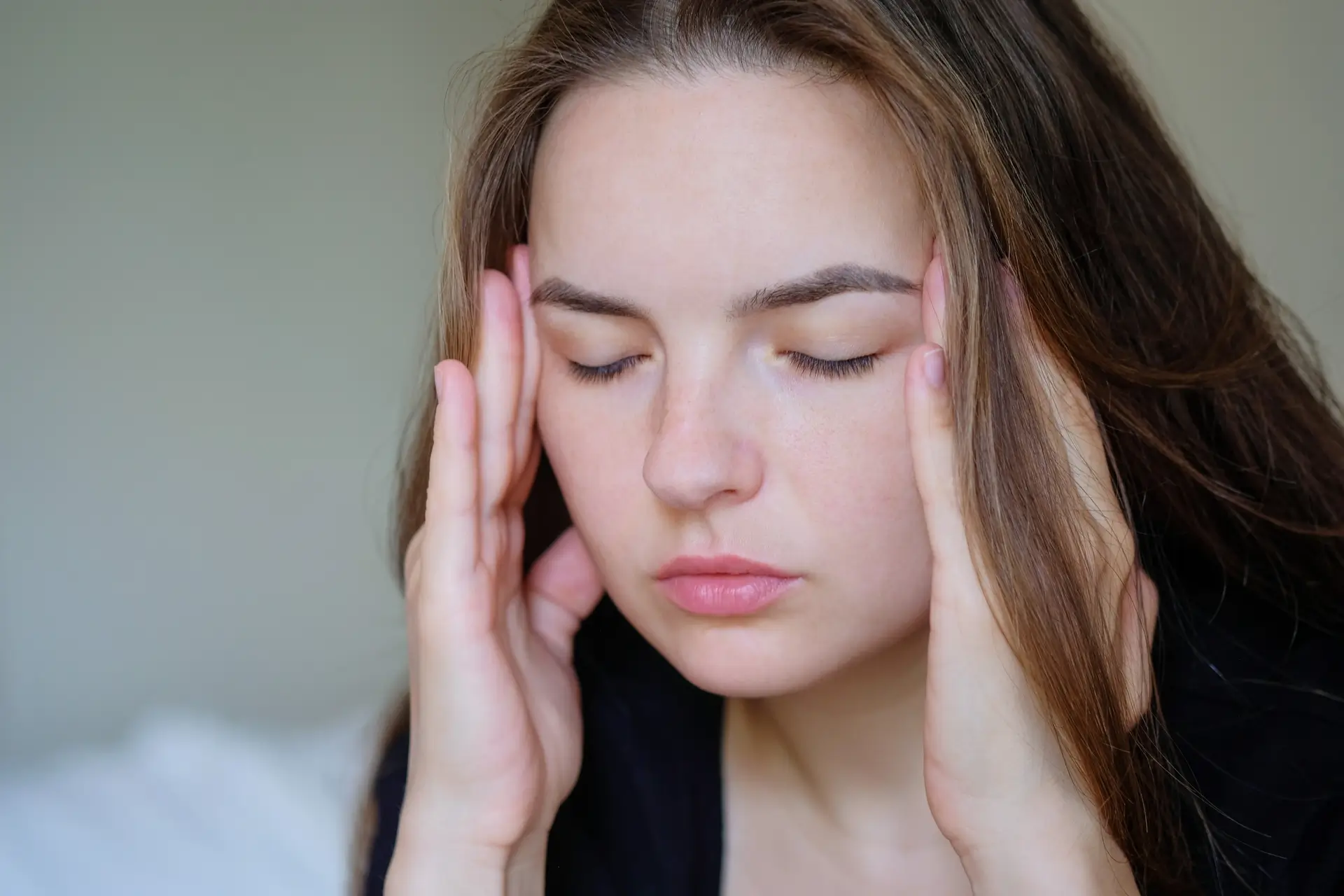 Woman holding her temples with eyes closed, representing pain relief and Stop the Throbbing Headaches with These Simple Physio Techniques for effective headache management.