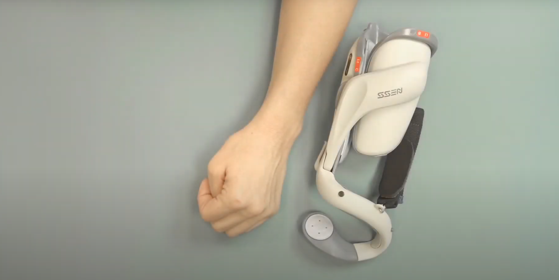 Hand Resting Next To A Bioness H200 Edmonton Neuroprosthesis Device Designed For Hand Rehabilitation And Mobility Support.