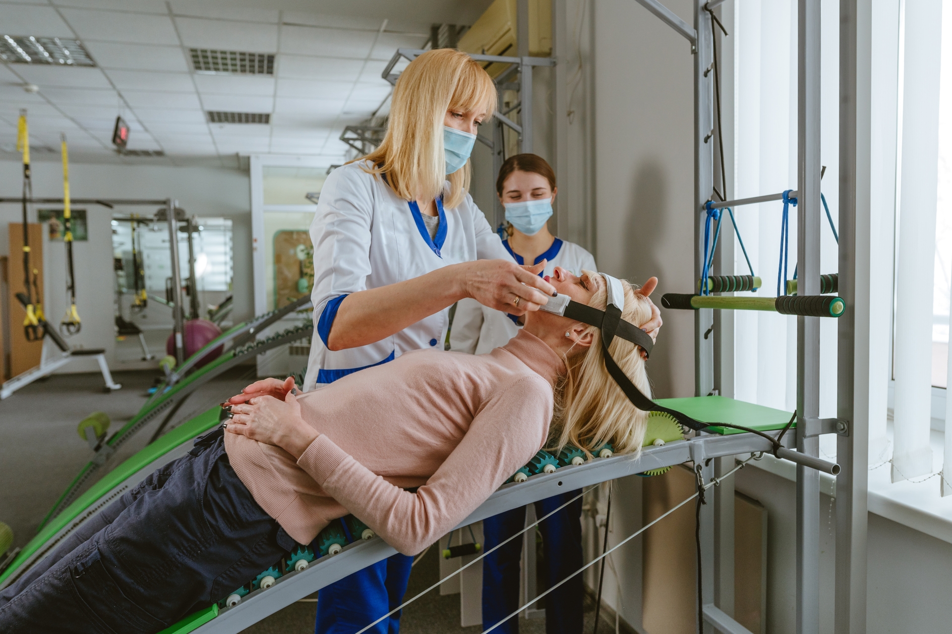 Therapist assisting a woman with a neck rehabilitation device in a clinic, demonstrating How does Physiotherapy help with Post-Stroke Swallowing Issues? through guided therapy techniques.