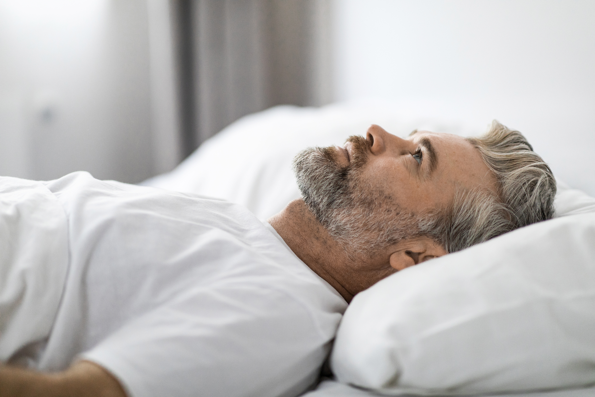 Man lying awake in bed reflecting sleep issues after brain injury