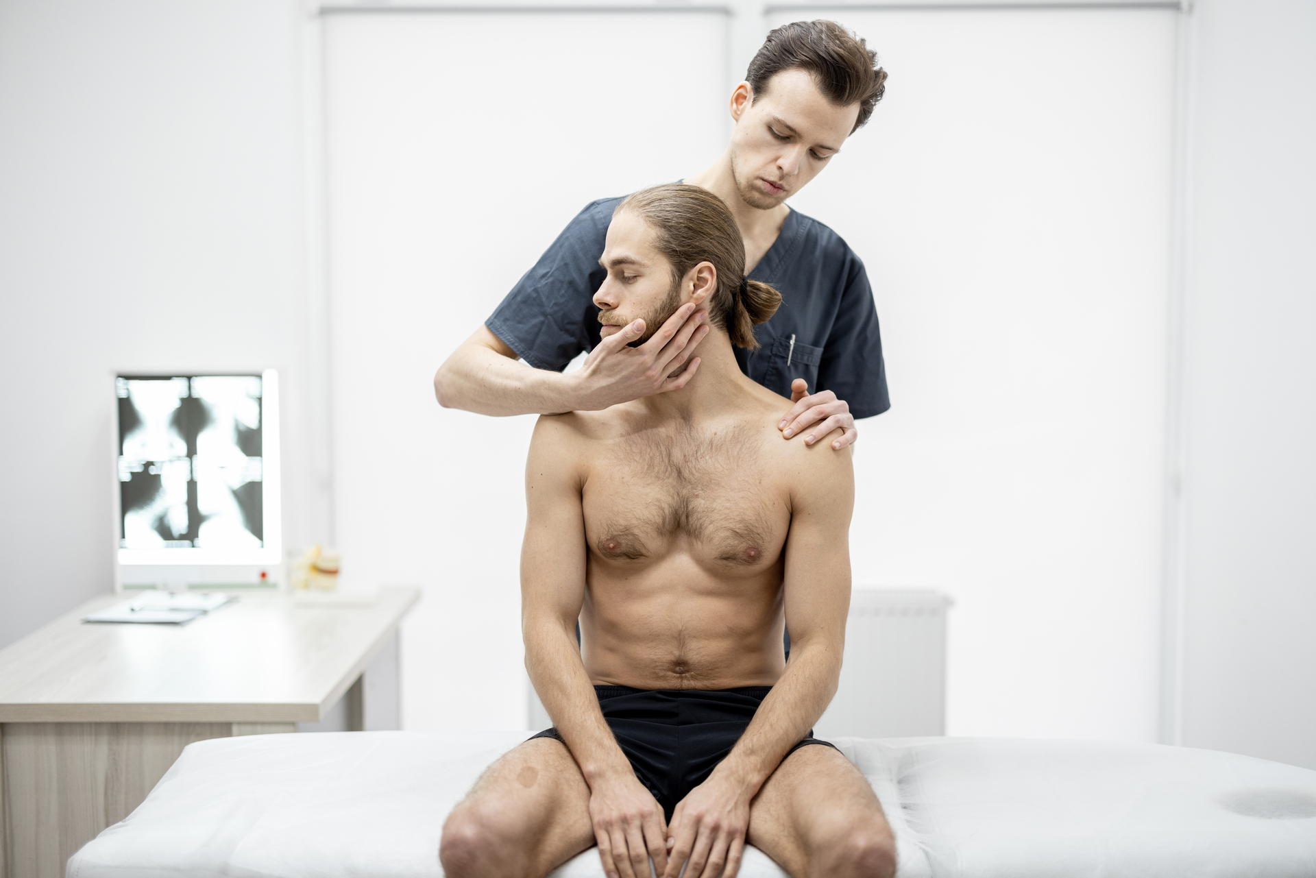 Therapist Performing Neck Manipulation During Manual Osteopathy In Edmonton Session On Male Patient In Clinic Therapist Performing Neck Manipulation During Manual Osteopathy In Edmonton Session On Male Patient In Clinic