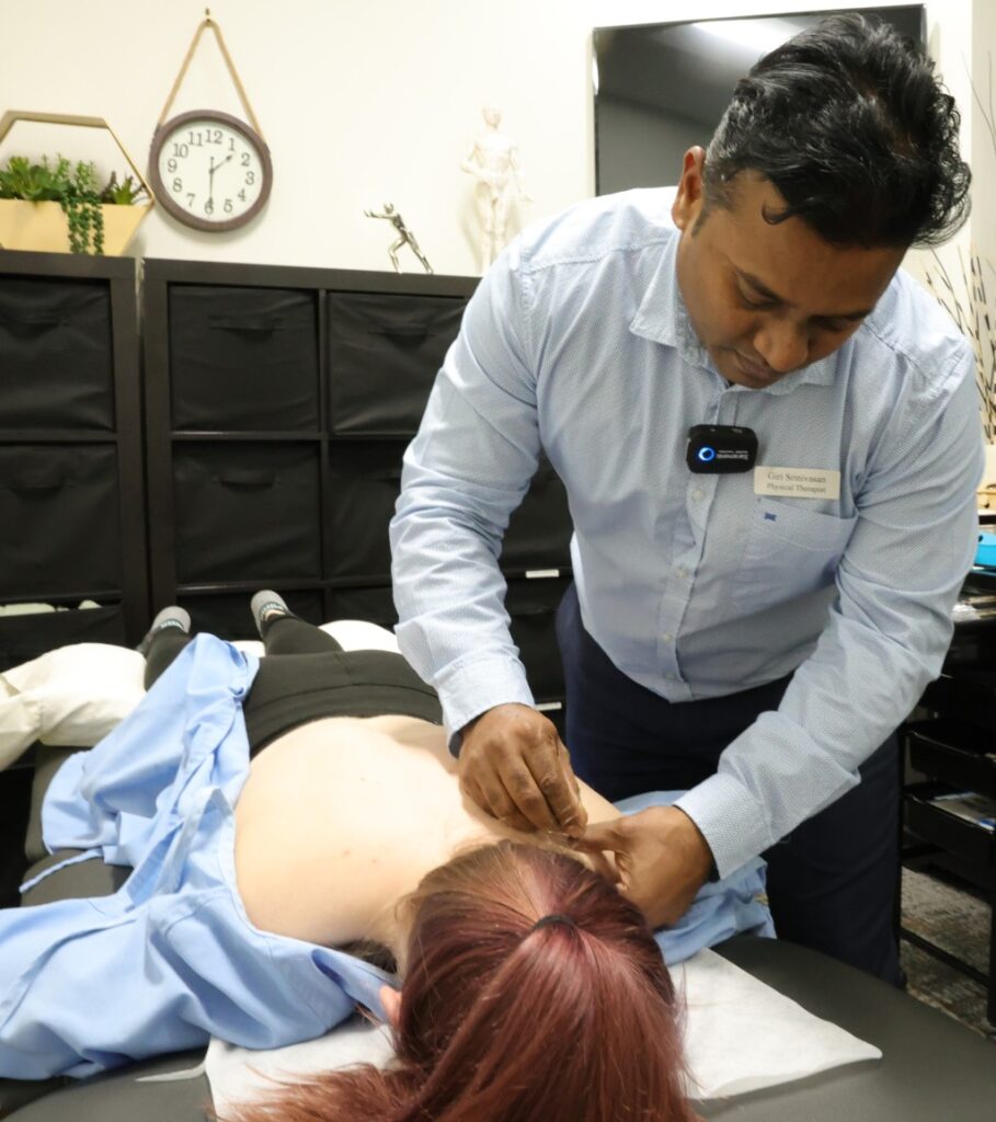 A Professional Performing Traditional Chinese Acupuncture By Placing Needles Along A Patient&Amp;Apos;S Back During A Physiotherapy Edmonton Session At In Step Physical Therapy.