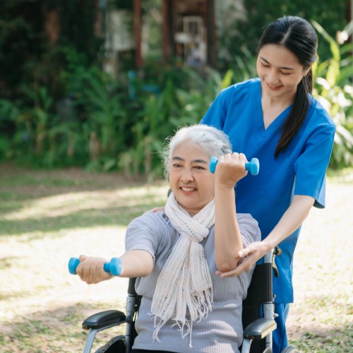 An Asian Physiotherapist Helping An Elderly Woman Perform Balance Exercises Using A Stability Ball During A Physiotherapy Edmonton Session At In Step Physical Therapy. An Asian Physiotherapist Helping An Elderly Woman Perform Balance Exercises Using A Stability Ball During A Physiotherapy Edmonton Session At In Step Physical Therapy.