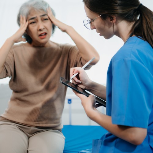 A Healthcare Professional In A White Coat Taking Clinical Notes While Discussing A Treatment Plan With A Patient During Physiotherapy Edmonton At In Step Physical Therapy. A Healthcare Professional In A White Coat Taking Clinical Notes While Discussing A Treatment Plan With A Patient During Physiotherapy Edmonton At In Step Physical Therapy.
