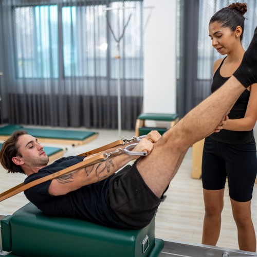 A Man Performing A Controlled Leg Exercise On A Pilates Reformer Bed To Improve Core Stability And Alignment During Physiotherapy Edmonton At In Step Physical Therapy. A Man Performing A Controlled Leg Exercise On A Pilates Reformer Bed To Improve Core Stability And Alignment During Physiotherapy Edmonton At In Step Physical Therapy.
