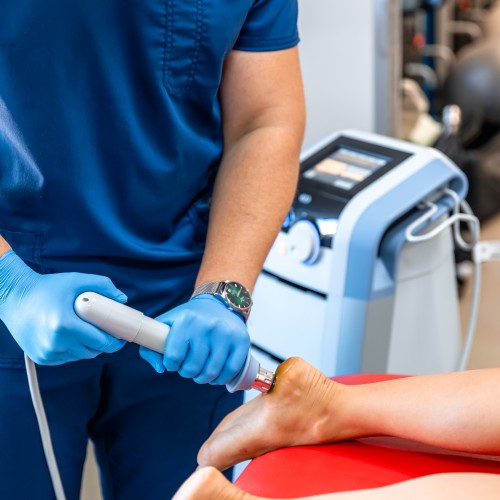 A Patient Receiving A Non-Surgical Shockwave Therapy Treatment On Their Foot, Highlighting Advanced Pain Management Options During Physiotherapy Edmonton At In Step Physical Therapy. A Patient Receiving A Non-Surgical Shockwave Therapy Treatment On Their Foot, Highlighting Advanced Pain Management Options During Physiotherapy Edmonton At In Step Physical Therapy.