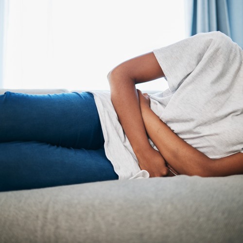 A Woman Sitting On A Bed And Holding Her Abdomen In Discomfort, Highlighting The Role Of Pelvic Health And Core Rehabilitation During Physiotherapy Edmonton At In Step Physical Therapy. A Woman Sitting On A Bed And Holding Her Abdomen In Discomfort, Highlighting The Role Of Pelvic Health And Core Rehabilitation During Physiotherapy Edmonton At In Step Physical Therapy.