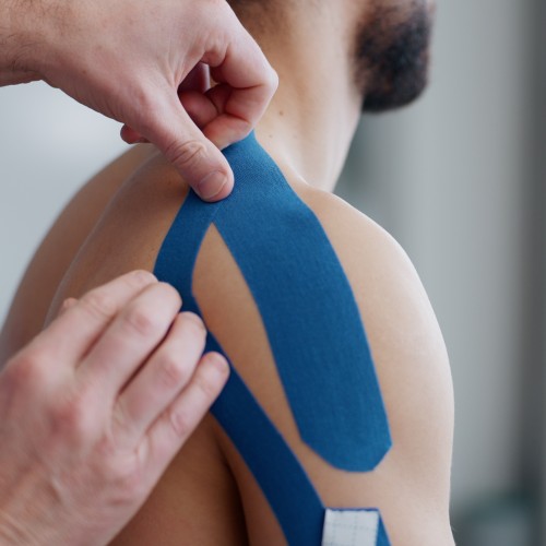 A Physiotherapist Applying Therapeutic Kinesio Tape To A Patient&Amp;Apos;S Hand And Wrist During A Physiotherapy Edmonton Session At In Step Physical Therapy. A Physiotherapist Applying Therapeutic Kinesio Tape To A Patient&Amp;Apos;S Hand And Wrist During A Physiotherapy Edmonton Session At In Step Physical Therapy.