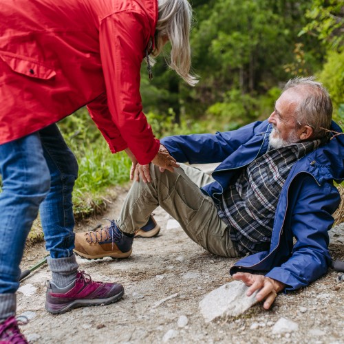 A Senior Man Sitting On A Mountain Trail And Holding His Injured Leg, Illustrating The Need For Sports Injury Rehabilitation During Physiotherapy Edmonton At In Step Physical Therapy. A Senior Man Sitting On A Mountain Trail And Holding His Injured Leg, Illustrating The Need For Sports Injury Rehabilitation During Physiotherapy Edmonton At In Step Physical Therapy.