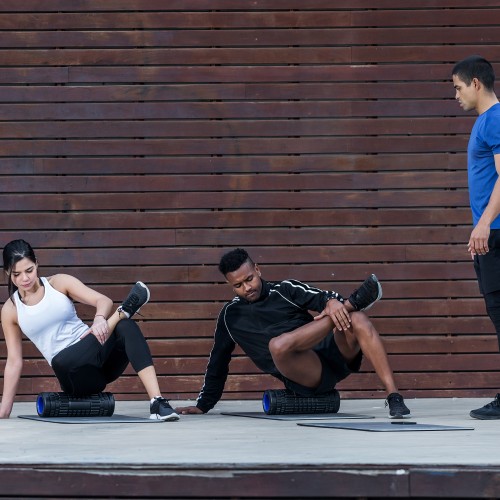 A Professional Trainer Supervising An Athlete Using A Foam Roller For Myofascial Release During A Physiotherapy Edmonton Session At In Step Physical Therapy. A Professional Trainer Supervising An Athlete Using A Foam Roller For Myofascial Release During A Physiotherapy Edmonton Session At In Step Physical Therapy.