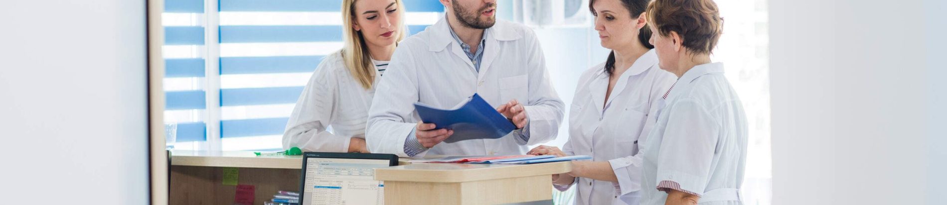 Healthcare professionals discussing patient records at a reception desk in a Massage Therapy Centre